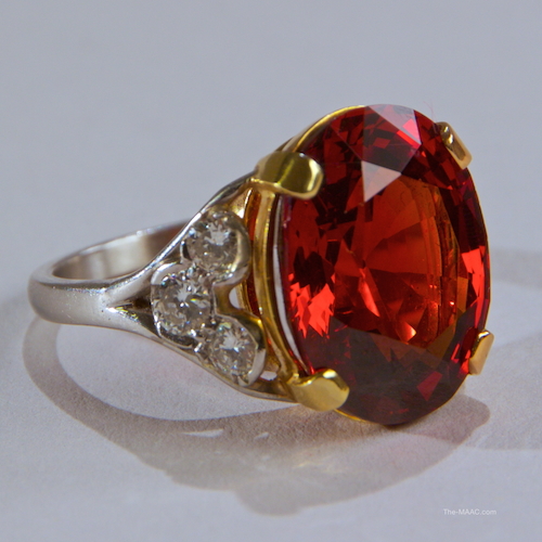 Spessartite Garnet and Diamond Ring. 15.45 cts red-orange oval Spessartite Garnet set into a platinum and 18 ct gold and diamond ring with six brilliant cut diamonds. With certificate from American Gemological Laboratories: Natural Stone. Spessartite Garnet, diamond, platinum, and gold. Spessartite from Madagascar, ring, USA. Late 20th century.