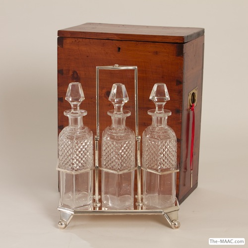 Tantalus with Traveling Campaign Box. Rare Tantalus–three spirit decanters in silver plate frame and teak campaign box with brass recessed handles and working key. Crystal, silver plate, teak and brass, England, 1870.